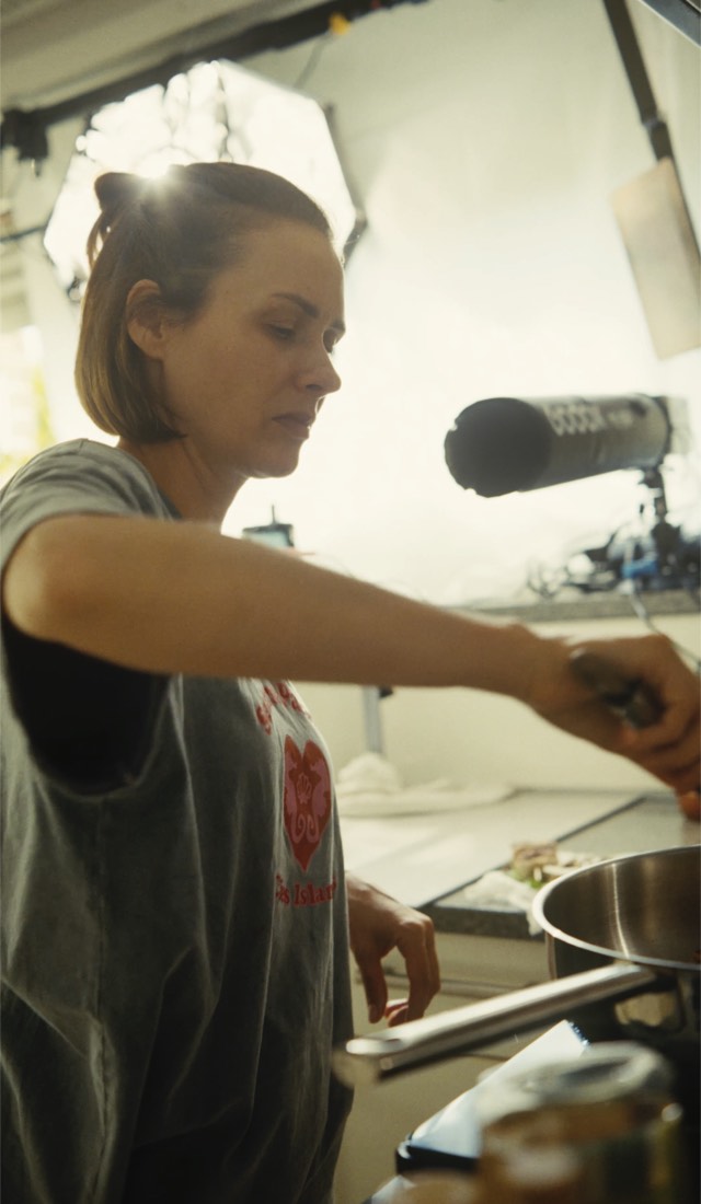 Sabrina kocht am Herd, darüber ein Richtmikrofon und eine Softbox